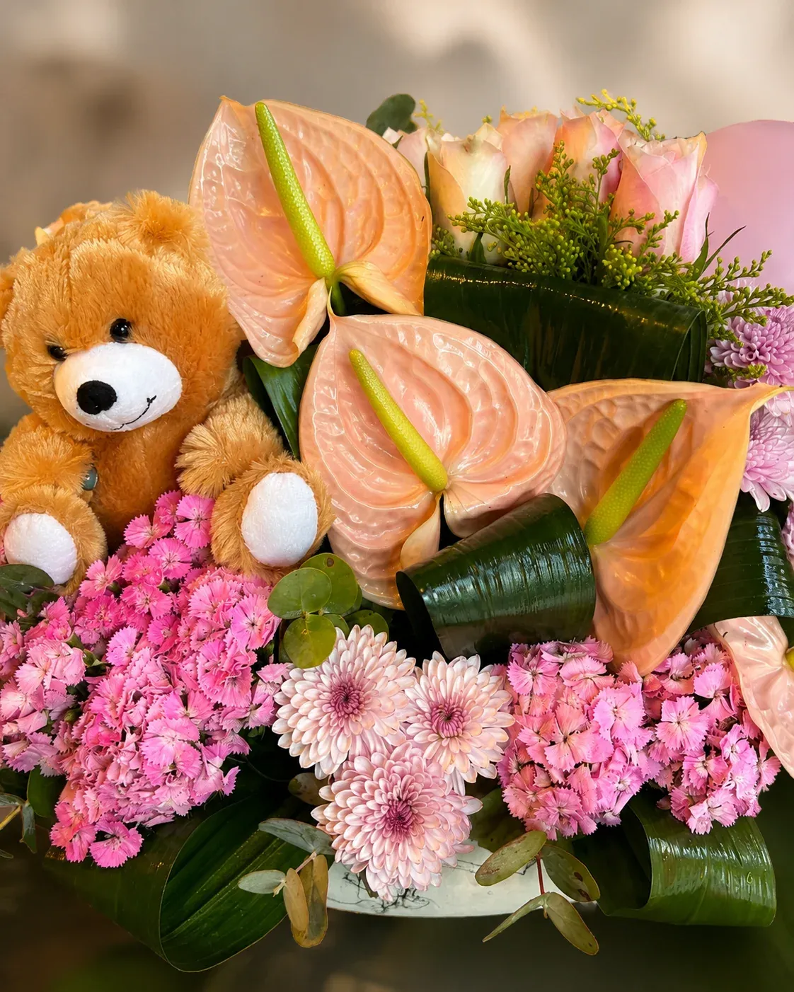 Peluş ayıcık, pembe balon, pembe antoryumlar, güller ve pembe çiçeklerle hazırlanmış gösterişli çiçek aranjmanı