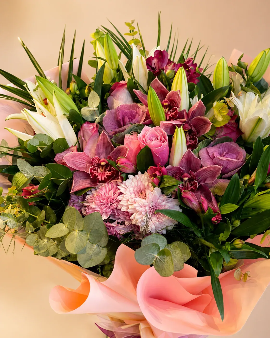 Pembe lilyum, beyaz lilyum, pembe gül ve bordo orkide detaylarıyla hazırlanmış somon ambalajlı premium çiçek buketi